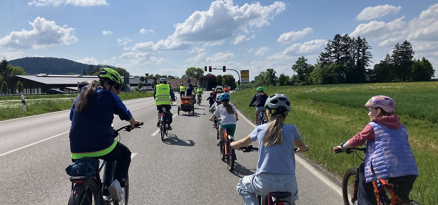 Platz da für Kinder auf dem Rad Die Fahrraddemo unterwegs auf der Landesstraße, die Kamera fährt hinter mehreren Kindern und einem Erwachsenen